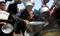 Des femmes et des enfants palestiniens tendent leurs casseroles vides devant une cuisine communautaire à Khan Younes, dans le sud de la bande de Gaza, le 21 août 2025 ( AFP / - )